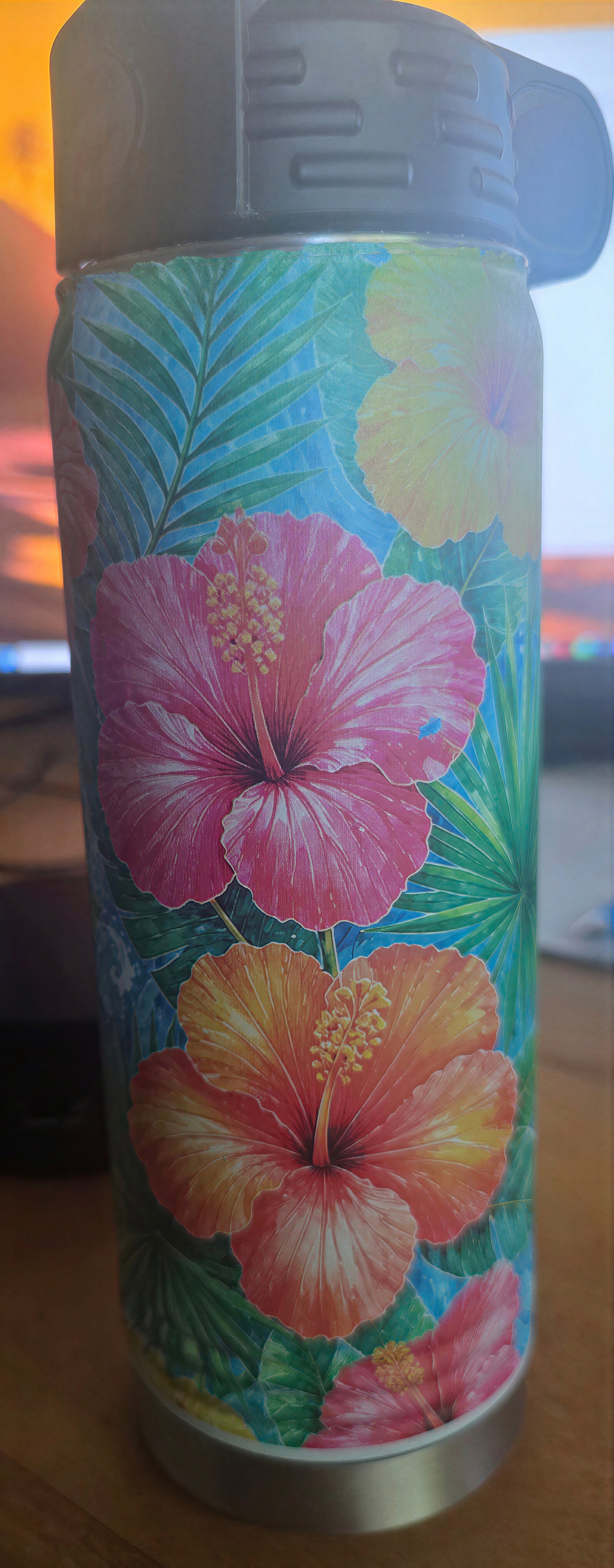 Alternate side detail of the tropical bottle showing magenta, coral, and yellow hibiscus flowers with palm leaves.