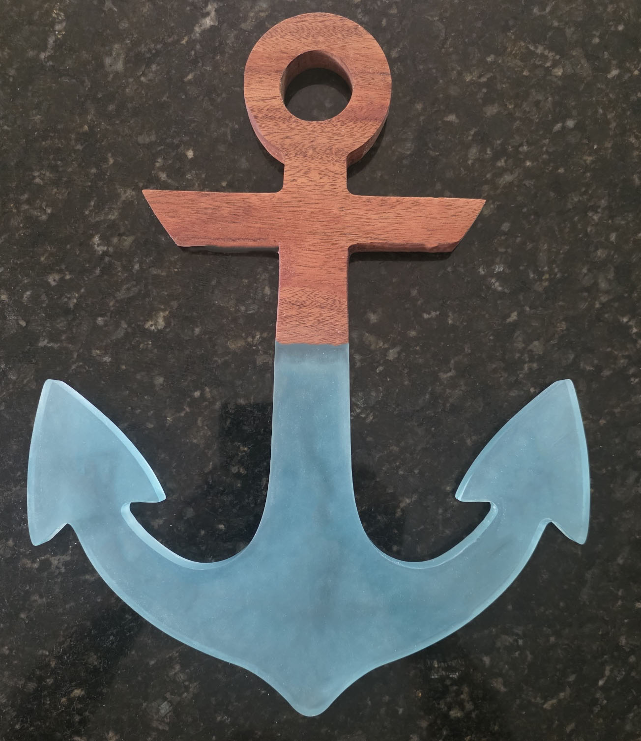 Mahogany and translucent ocean-blue resin anchor on a dark stone background