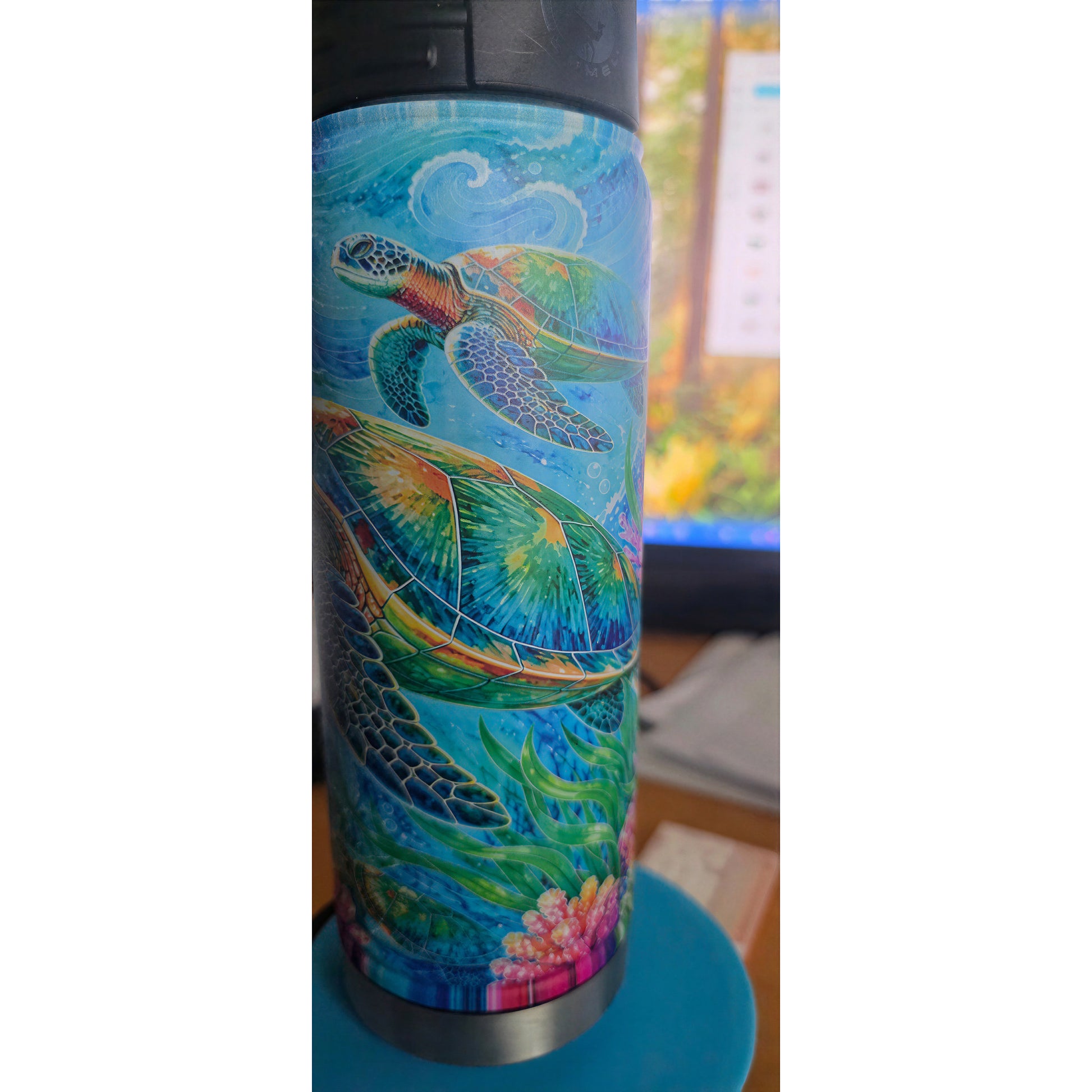 Side view of the bottle showing two colorful sea turtles swimming above coral and sea plants.