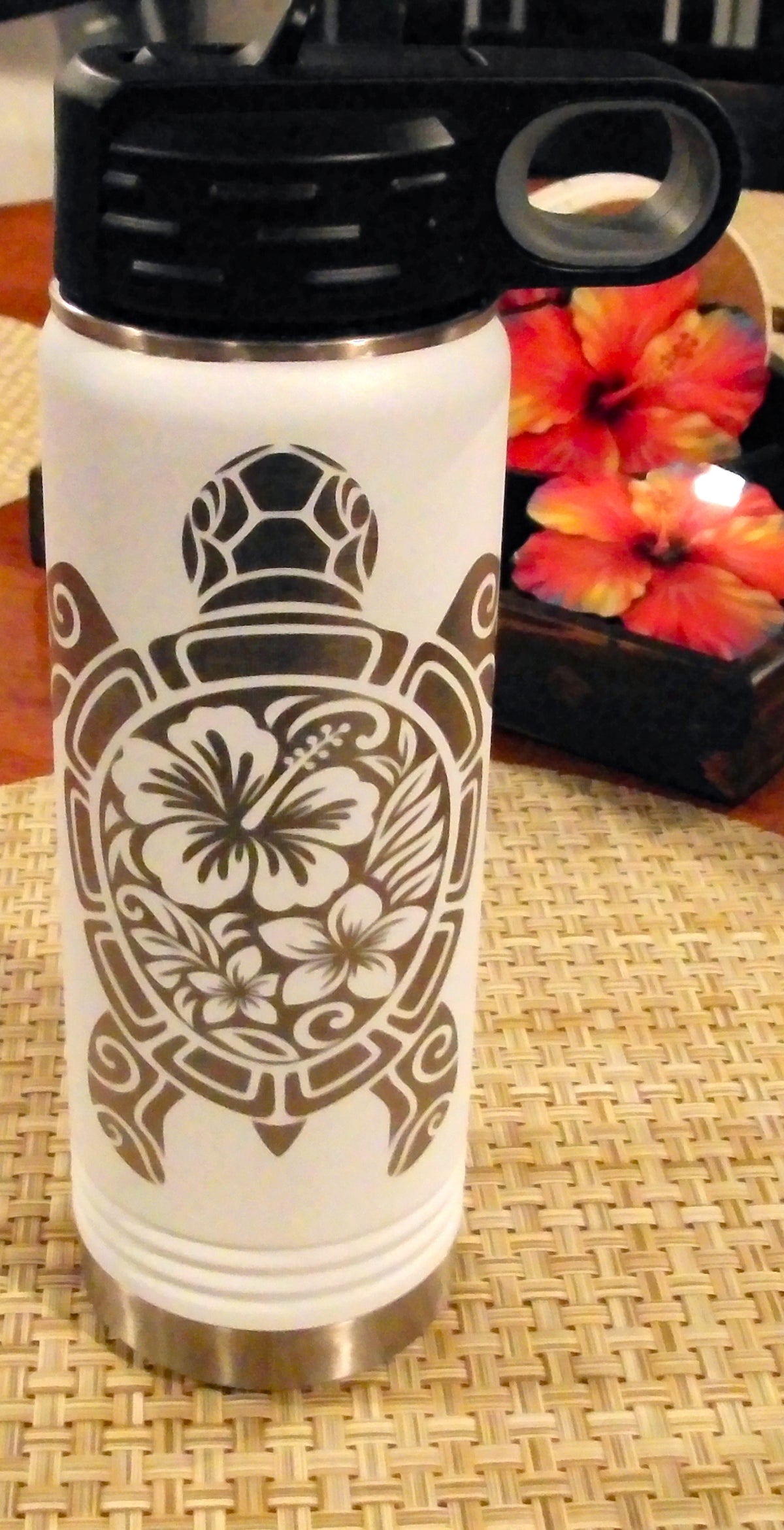 Alternate view of the white bottle showing the full silver tribal turtle engraving and black handled lid.